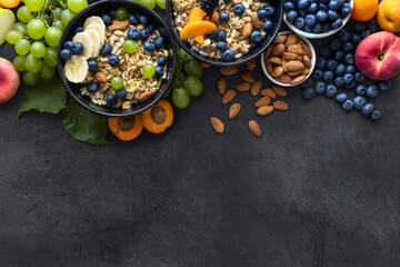 Top view healthy breakfast bowls with ingredients granola fruits greek yogurt and berries on dark...