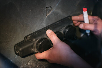Obraz premium Electrician installs an external electrical outlet on the wall close up.