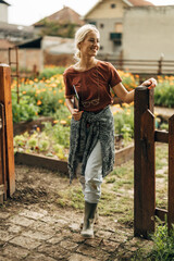 Obraz premium Satisfied woman goes out of her eco garden.