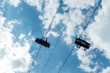 Mountain four-seater chairlift on the background of a blue cloud sky.