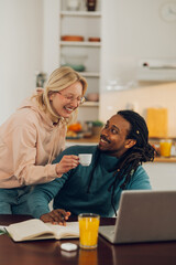 A happy woman is bringing her interracial working husband a cup of coffee.