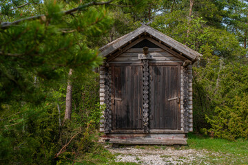 Fototapeta na wymiar Wooden public toilet in the Estonian forest near the public rest and barbeque RMK area on a cloudy summer day. Kassari, Saaremaa, Estonia