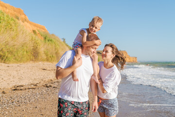 family with little son walk along seashore on a sunny day, the concept of family and vacation