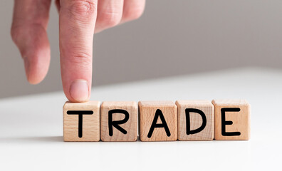 Hand flips cubes and changes the word 'train' to 'trade'. Beautiful wooden table, white background, copy space. Business concept.