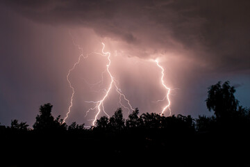beautiful lightning during a thunderstorm at night in a forest that caused a fire, against a dark...