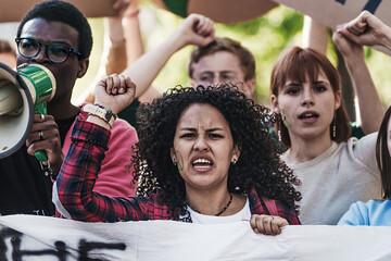 Student's protesting with raised fist - main focus on a curly haired woman with a peace sign on her...