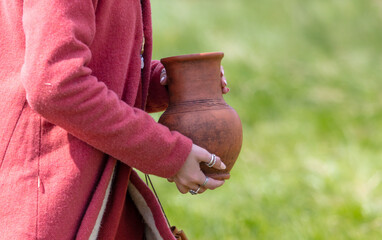 Woman in medieval dress holding a clay jug in her hands. Selective focus