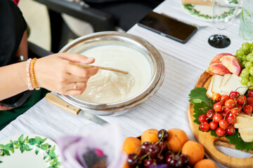Making cheese from goat milk at home. Female and stir cheese sourdough with a spoon in a saucepan. Technology of cooking cheese. Cheese-making processes. Cooking concept