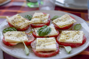 Caprese salad, slices of tomato, cheese of mozzarella ann spices, typical mediterranean meal