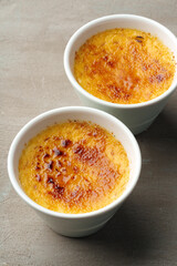 Creme brulee with caramel in two white bowls on gray background