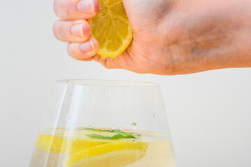 Cytryna wyciskana w dłoniach do szklanki z wodą 