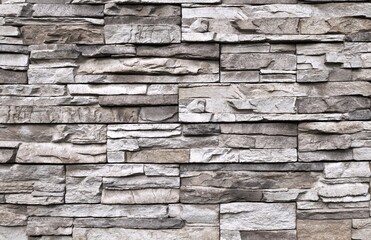 Stone cladding wall made of striped stacked slabs of gray  rocks with shades of gray color. Panels for exterior. Background and texture.