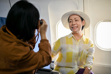 An Asian granddaughter is taking photos of her grandmother during the flight