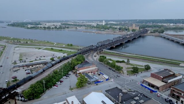Train moving over Mississippi River railroad bridge in Davenport, Iowa with drone video moving in.