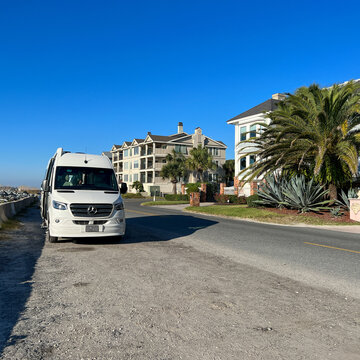 A RV Van parked a long side the beach during the day while on a road trip in St. Simeons Island, GA.