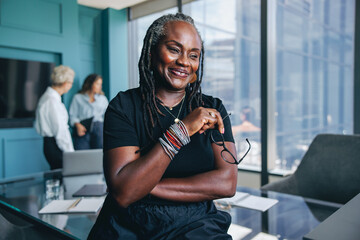 Black female professional sitting on a boardroom table in a business office