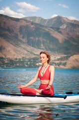 Fototapeta na wymiar Woman doing yoga on sup board. Healthy lifestyle