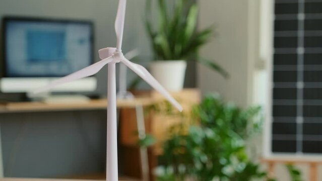 Tilt up shot of plastic model of wind turbine on table in engineers office