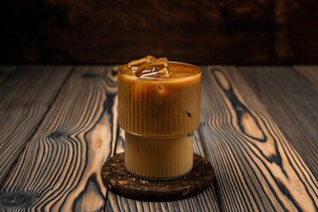 Close-up of iced latte cold refreshing summer coffee drink in a glass on wooden background