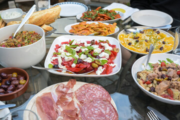 Summer dinner table with various salads, snacks and bread for a party meal with friends or family, selected focus