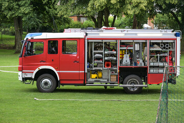 German fire engine, red truck with open roller shutter doors and the equipment for firefighting...