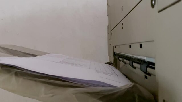 Paper out from Printer, scanner or laser copy machine. Printed sheet of paper is coming out from the exit of the office printer - Printed paper
