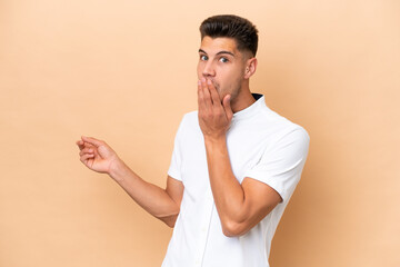 Young caucasian man isolated on beige background with surprise expression while pointing side