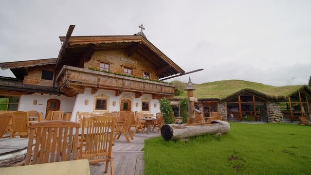 Austria, Going am Wilden Kaiser 2023: Rustic hotel in the mountains shot with lot of green grass and patio furniture. Two storyes hotel and outside place for dining.