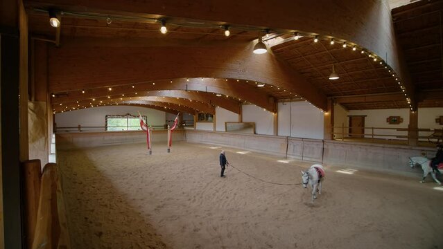 Austria, Going am Wilden Kaiser 2023: Horsemanship training by male in non obstacle arena. Big hall for training horse riding for equestrianism.