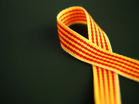 Senyera catalana flag ribbon on a dark background. La diada catalana concept. Copy space to add text 
