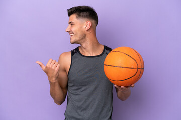 young caucasian woman  basketball player man isolated on purple background pointing to the side to present a product