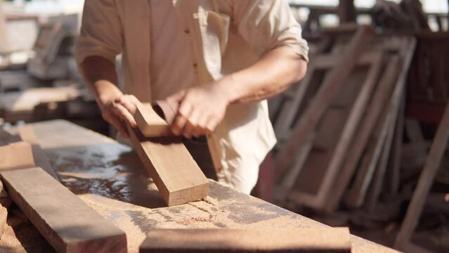 A carpenter polishing a prank of wood with sandpaper by hand. Carpentry, Craftsmanship, woodworking.