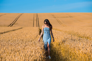 Naklejka na ściany i meble beautiful young woman in golden wheat field