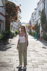 Pretty blonde young girl with white tank top in the town of Mogan