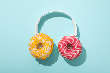 Donuts and headphones on blue background, top view