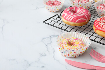 Donuts on the grid, fork and knife on marble background, space for text