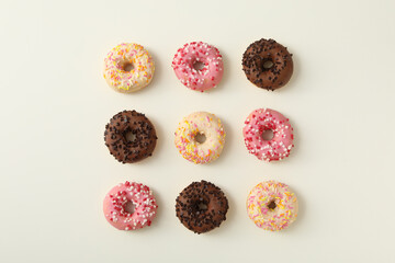 Fototapeta na wymiar Chocolate, white and pink donuts on white background, top view