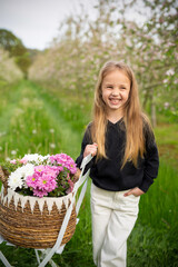 A cute girl in a blooming apple garden with flowers