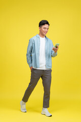 Adult Asian man walking relax while looking to the camera and holding mobile phone