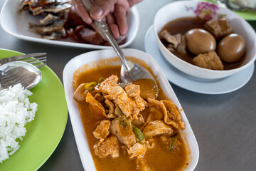 Close up of hand eating panang curry with pork