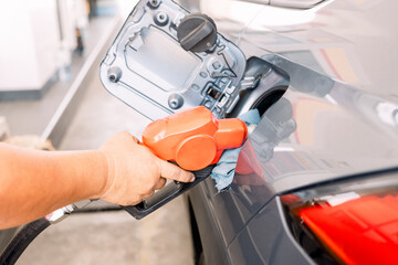 The hand of a gas station worker fills up the car tank. The expense of petroleum. Petrol price and oil crisis concept.