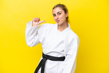 Young caucasian woman doing karate isolated on yellow background proud and self-satisfied