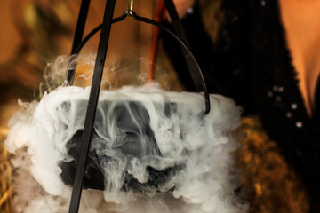 The magic Witch's cauldron potion conjures in the wizarding lair. Halloween pumpkin head on wooden...