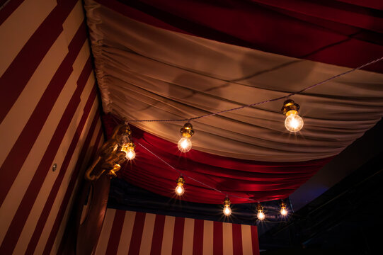 Ceiling decorated with heavy fabrics and light bulbs to show a circus feeling