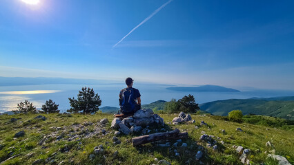 A man sitting on top of Vojak and enjoying the panoramic view on Mediterranean Sea. The mountain is...