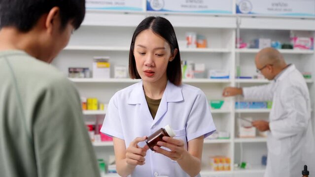 Beautiful asian female pharmacist analyzing about customer symptoms for discussion of the medicine property effect with tablet and customer buying pill under prescription order. 4k resolution.