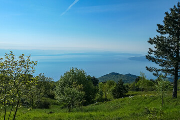 A panoramic view on the Mediterranean Sea in Croatia from Vojak. The mountain is overgrown with lush green plants. Few islands in the back. Early morning hiking by the sea. Clear, blue sky. Remedy