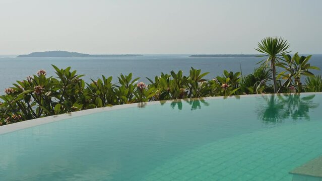 Slow calming pan over the infinity pool with views across the Gilli islands in Indonesia