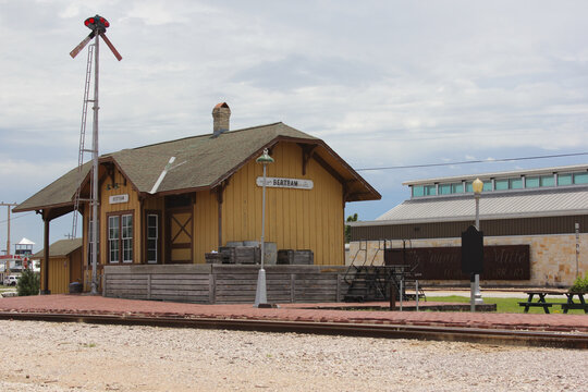 Bertram, TX - June 8, 2023: Historic Train Depot with Library in Background on Cloudy Day in Bertram Texas