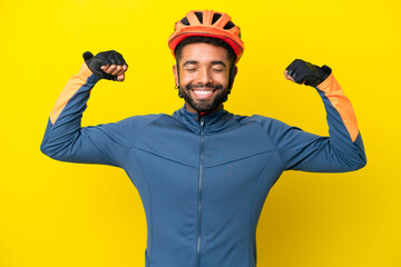 Young cyclist Brazilian man isolated on yellow background doing strong gesture